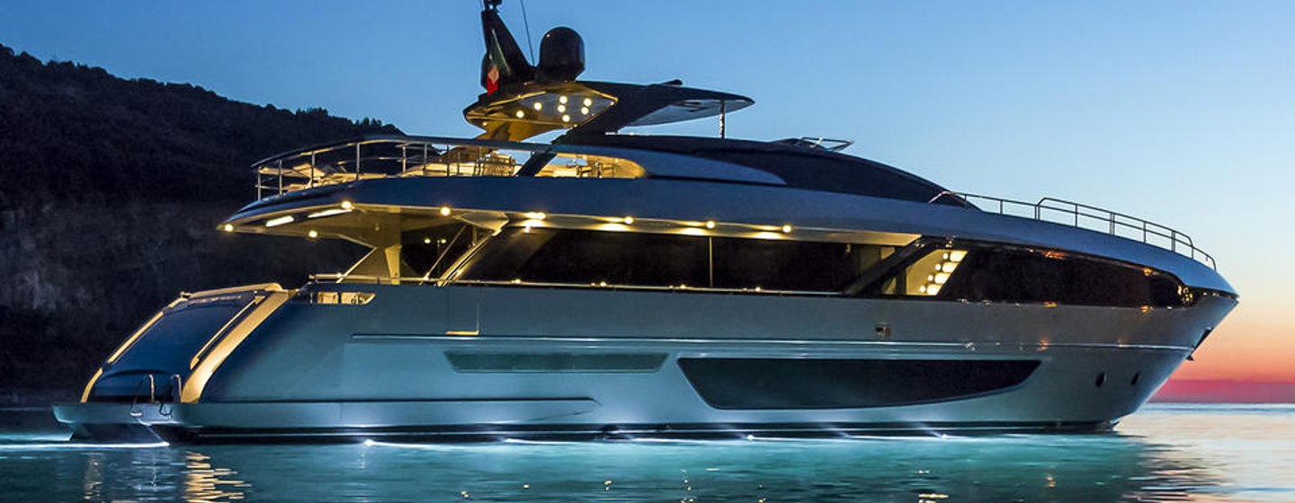 Side view of Riva Corsaro 100 underway at dusk, surrounded by elevated terrain in background