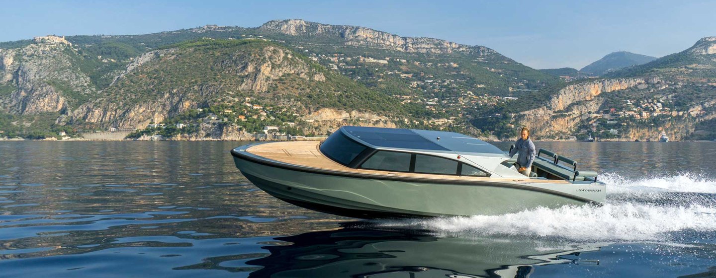 Enclosed limousine tender moving fast on water with hills in background