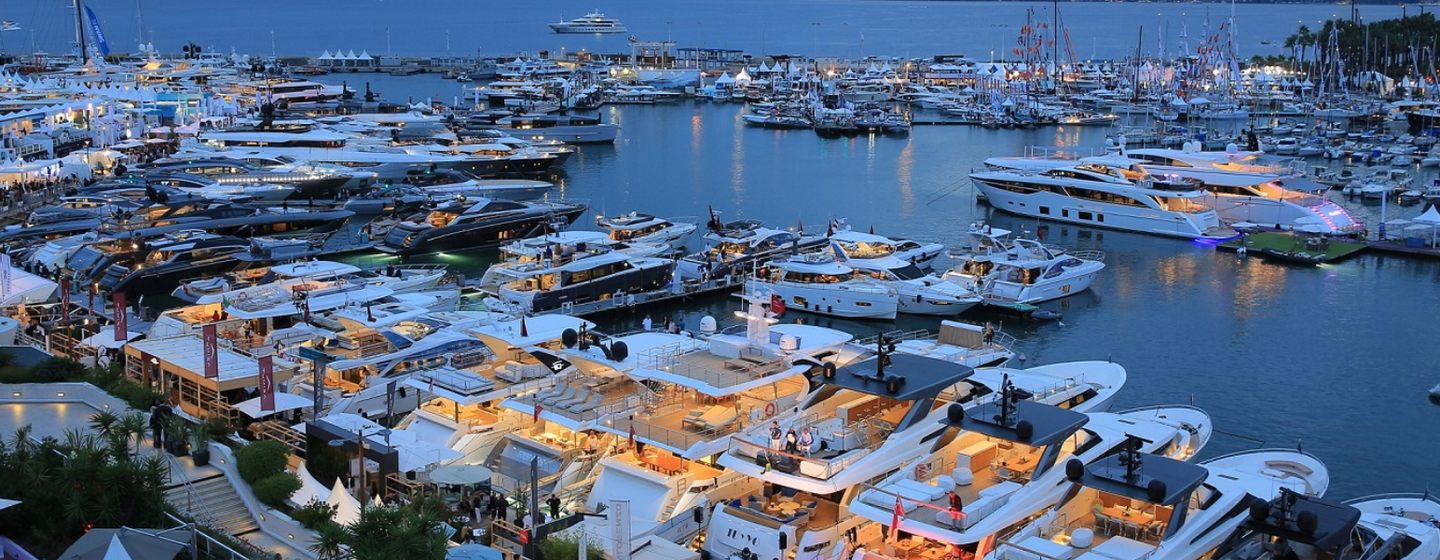 Elevated view of Cannes Yachting Festival at dusk, surrounded by sea with multiple motor yachts in foreground