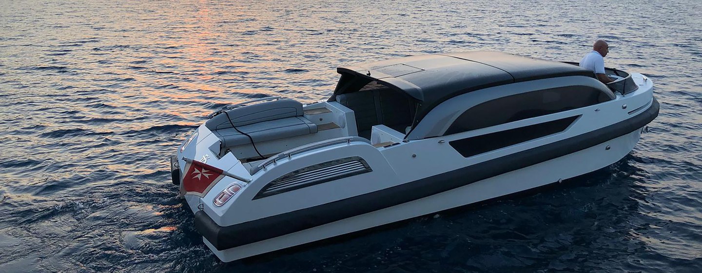 Elegant limousine tender on calm water at sunset with hills in background