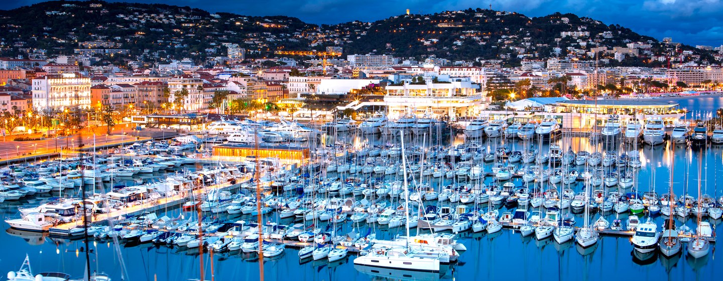 Cannes harbour at night with mountainous background