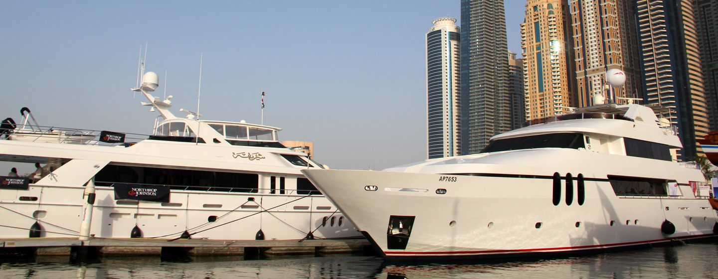 Superyachts moored in front of Dubai skyline, surrounded by sea