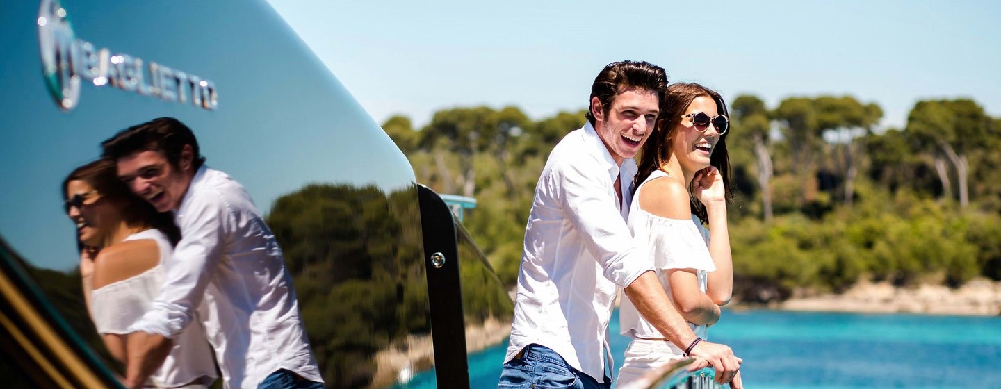 Young couple on back of yacht looking happy with clear water and hills in background