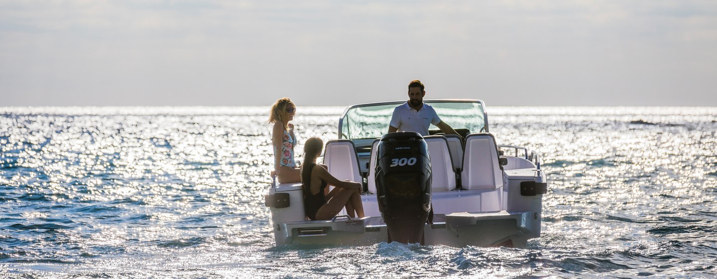 Tender boat viewed from behind, with motor prominent. Two female guest and one male guest talking. The boat is still on the water.