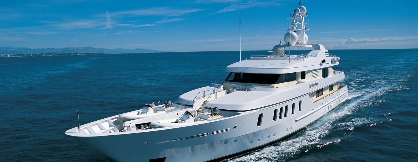 Feadship yacht ADVENTURE in running shot mid aerial towards port bow and along side profile, blue sky and calm sea, yacht making fair speed as wake being created