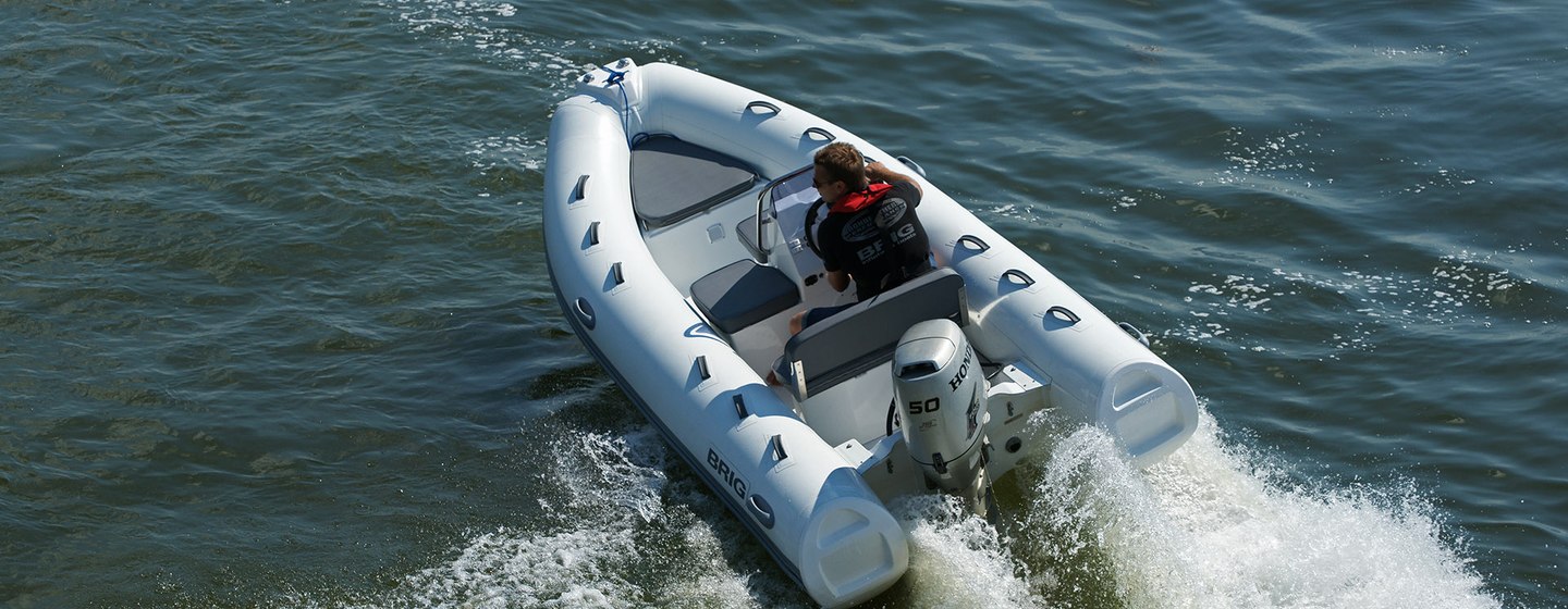 RIB tender with one person viewed from above, with spray emanating from behind