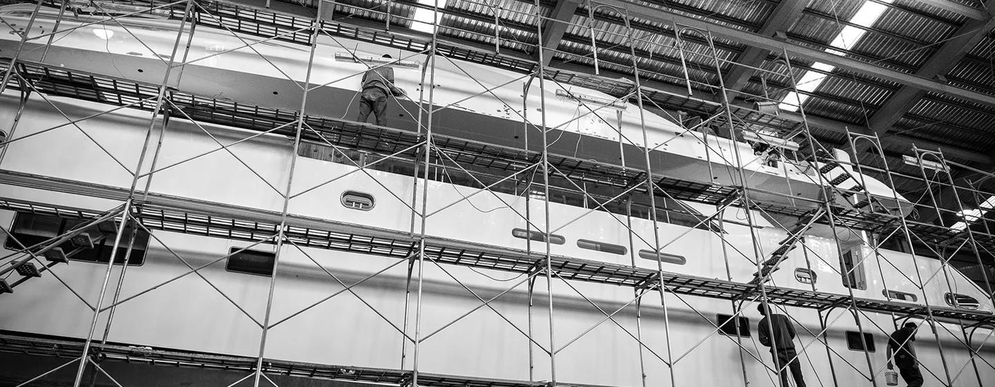 Workers on scaffolding on superyacht in shipyard