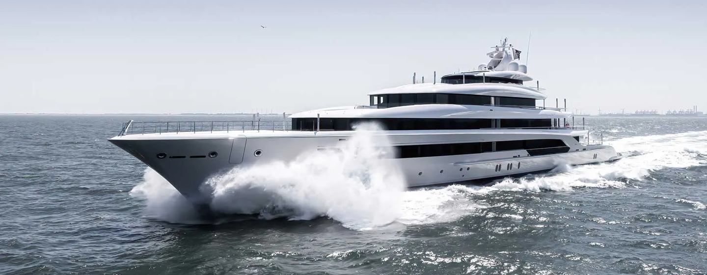 Oceanco yacht H3 shown in running shot, making way at speed in smooth sea, on grey day, port bow and side profile, waves crashing on bow