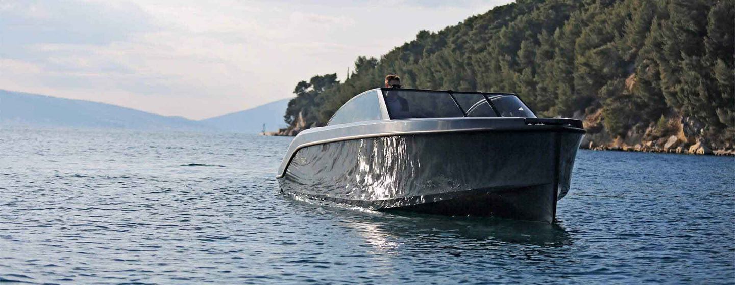 Rand Boat Leisure 28 powerboat shown still in calm waters, with land in background. View from water level towards starboard bow