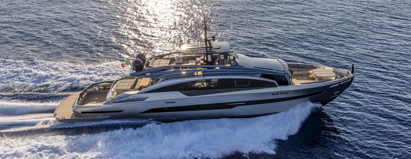 Pershing yacht AGARTHA shown in running shot over starboard side profile in calm waters, sun casting light on water in background, creating wake so clearly moving at speed