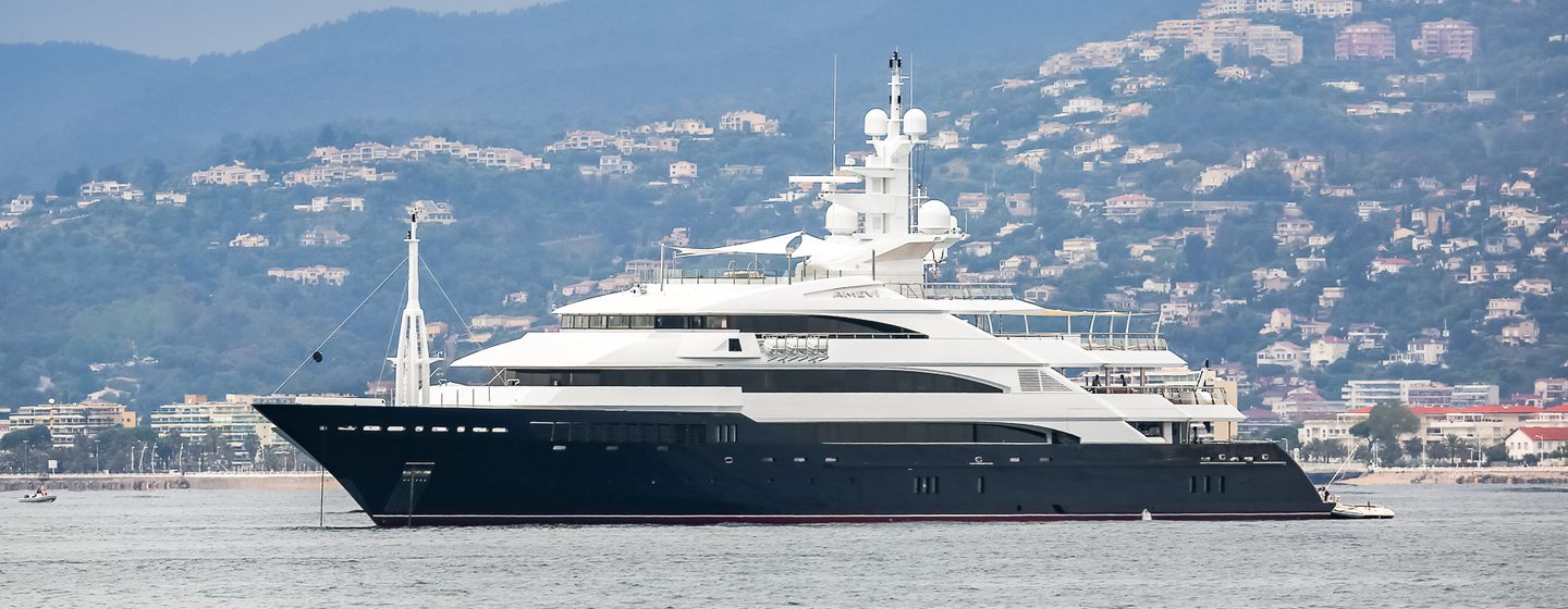 Oceanco superyacht AALTO is for sale at Monaco Yacht Show 2024, the image shows the megayacht on anchor in calm sea, on a hazy day with land in background