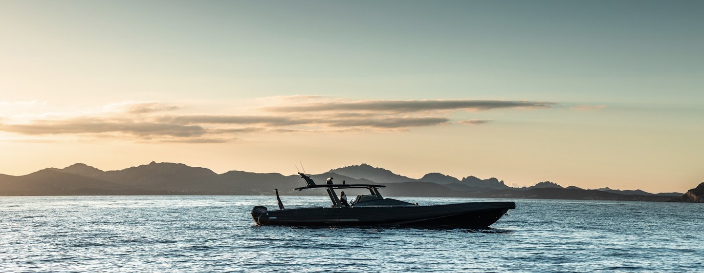 Chase boat on sea at sunset with mountains in background