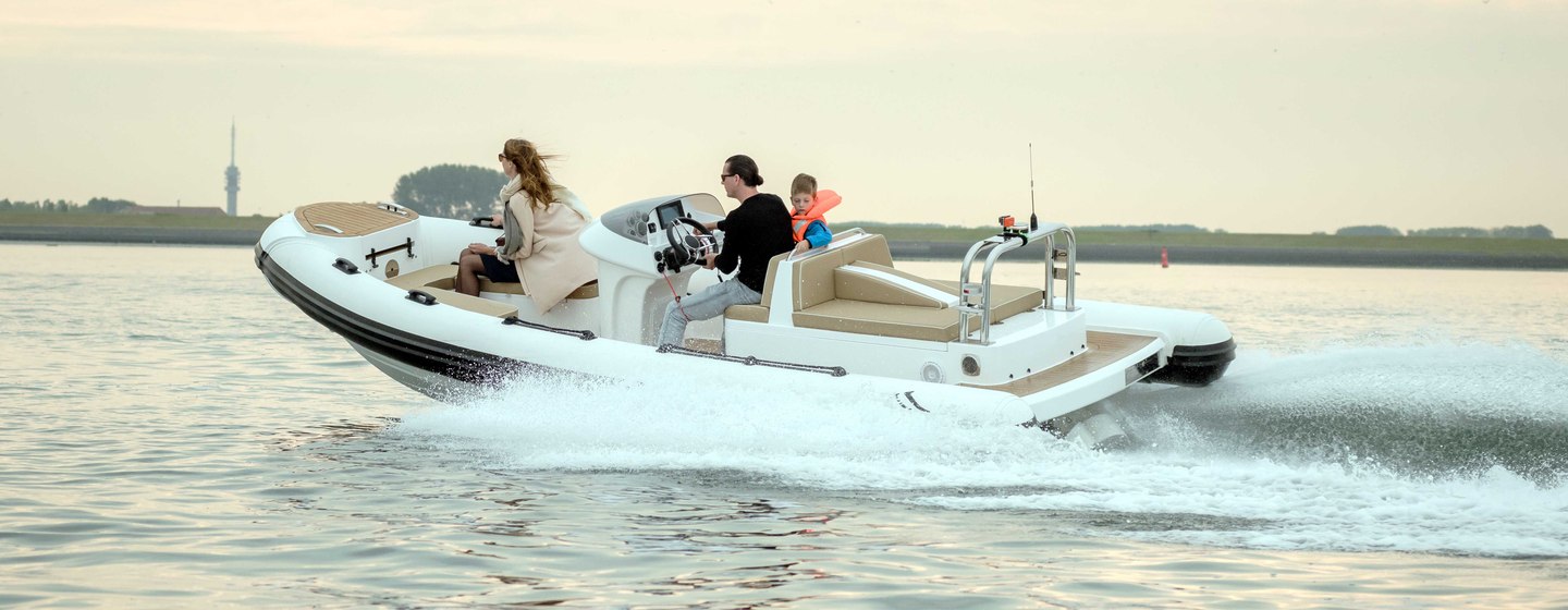 Family of three on RIB tender moving at speed across water