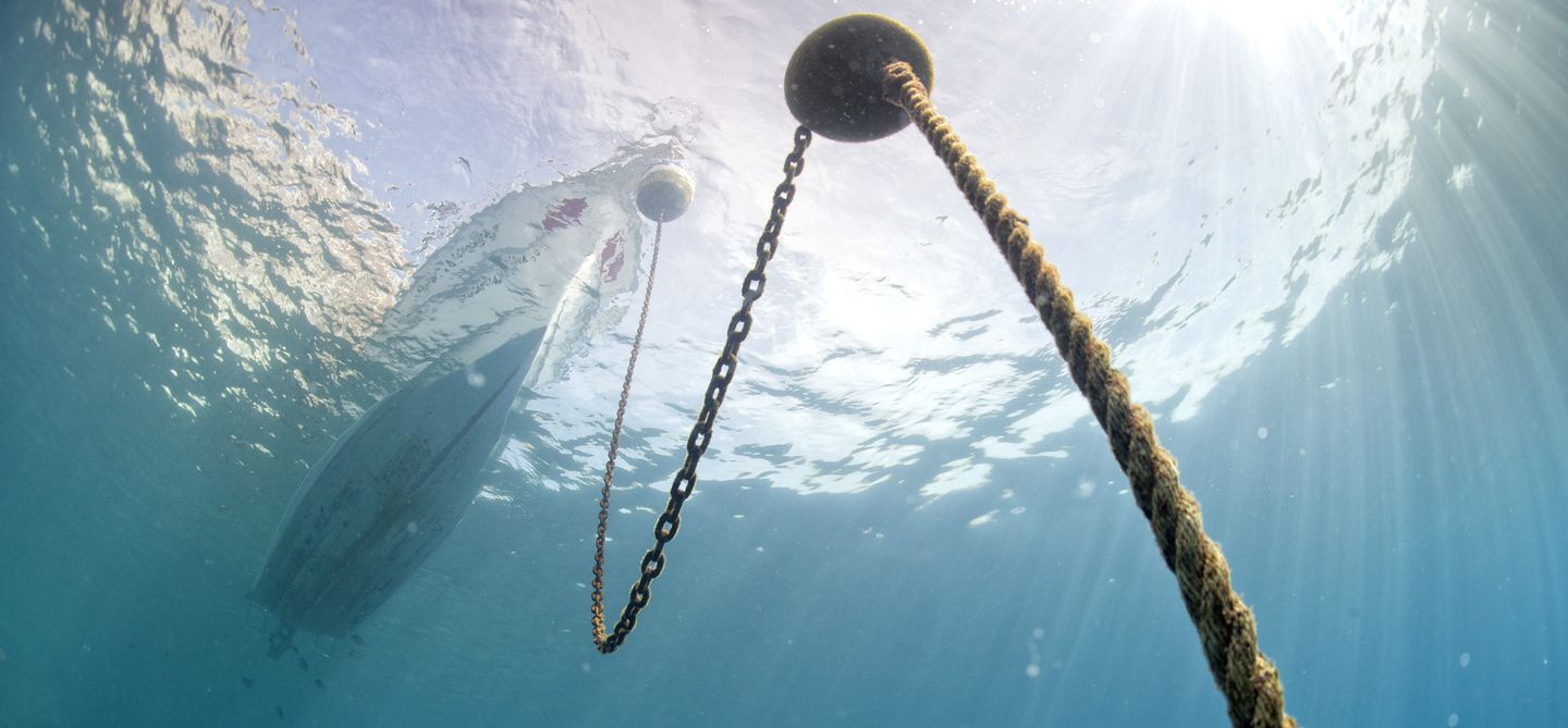 Yacht viewed from underwater with anchor