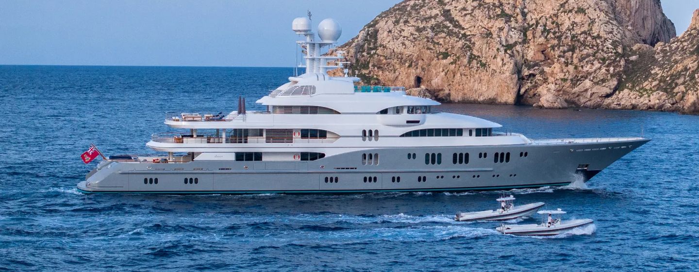 Superyacht Rocinante under way next to tenders and rocks