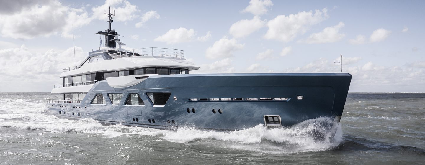 Superyacht Amels 60 on sea trials, shot from water level looking at starboard bow and wide profile, cloudy day, smooth sea