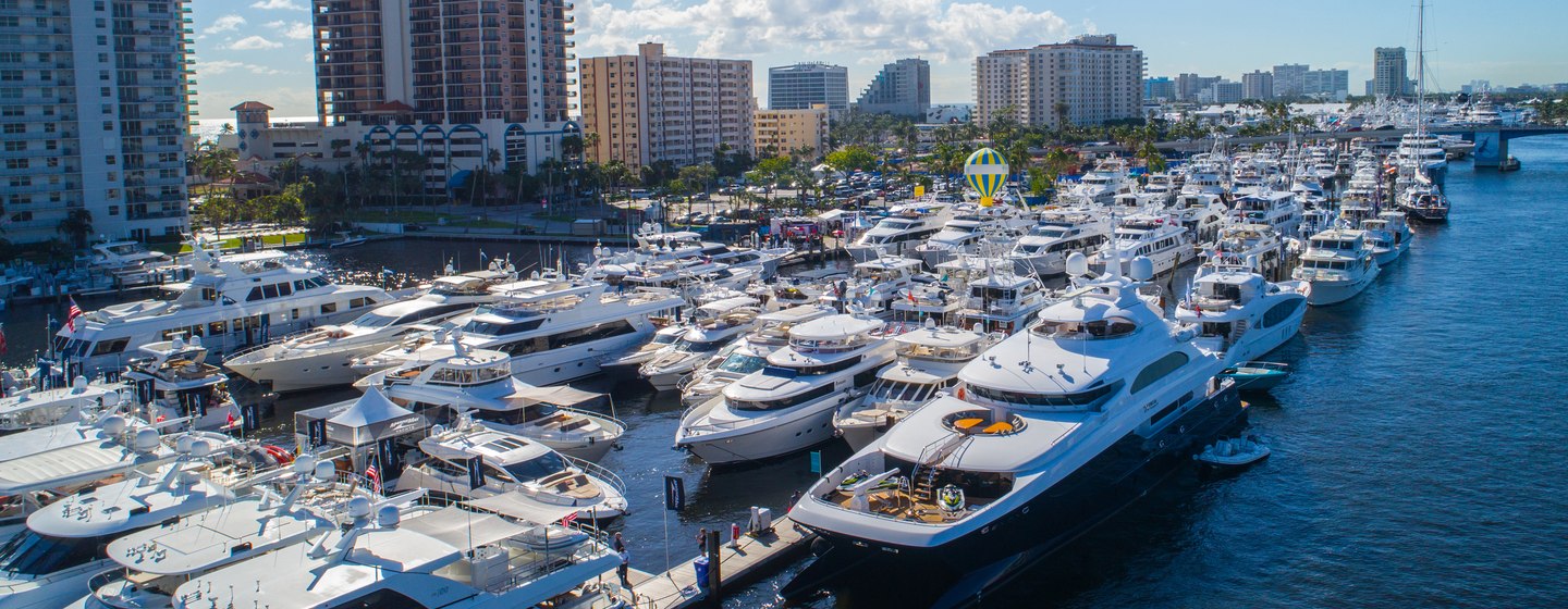 Yachts lined up at FLIBS with large buildings in background