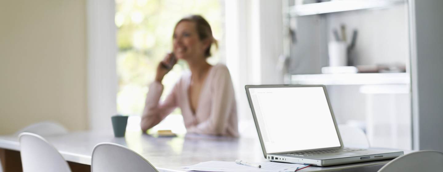 Woman at desk with computer while on the phone 