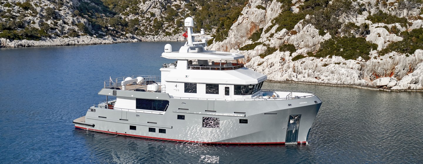 Bering B77 VERONIKA on water with rugged coastline backdrop