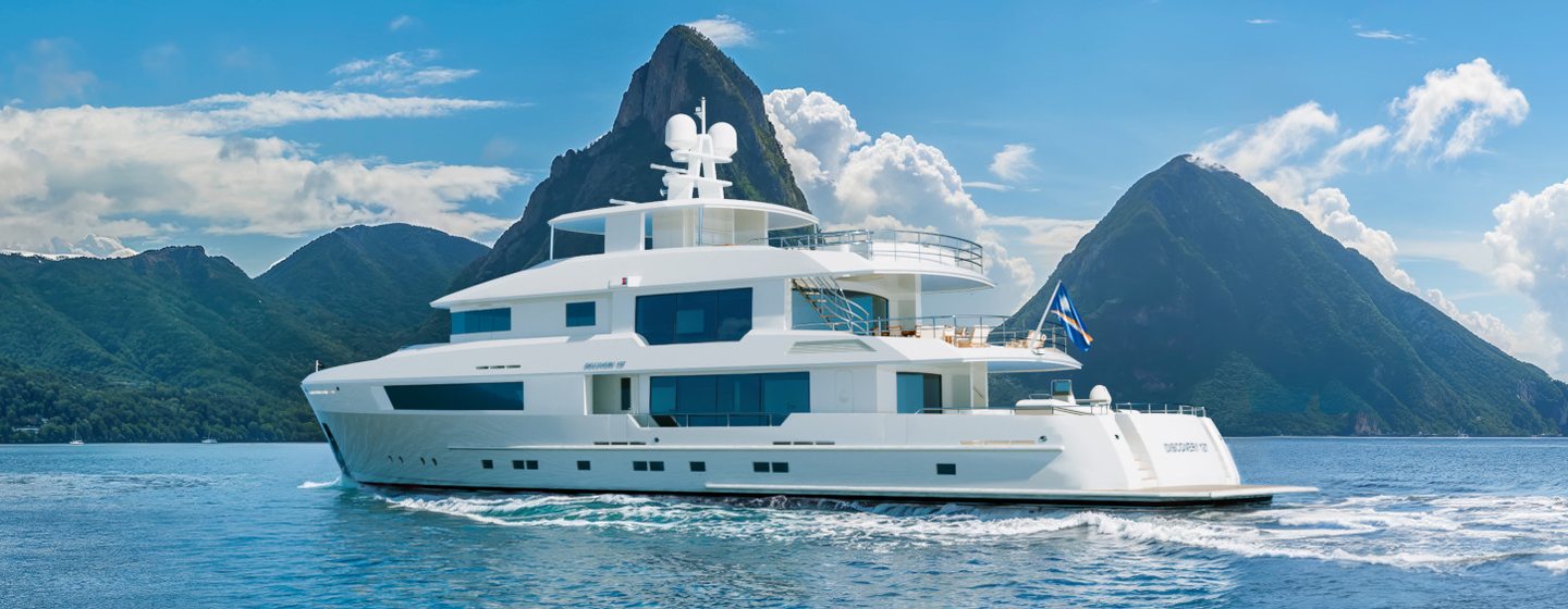 The Cheoy Lee 127 Discovery explorer yacht running through a calm sea in front of a rocky landscape