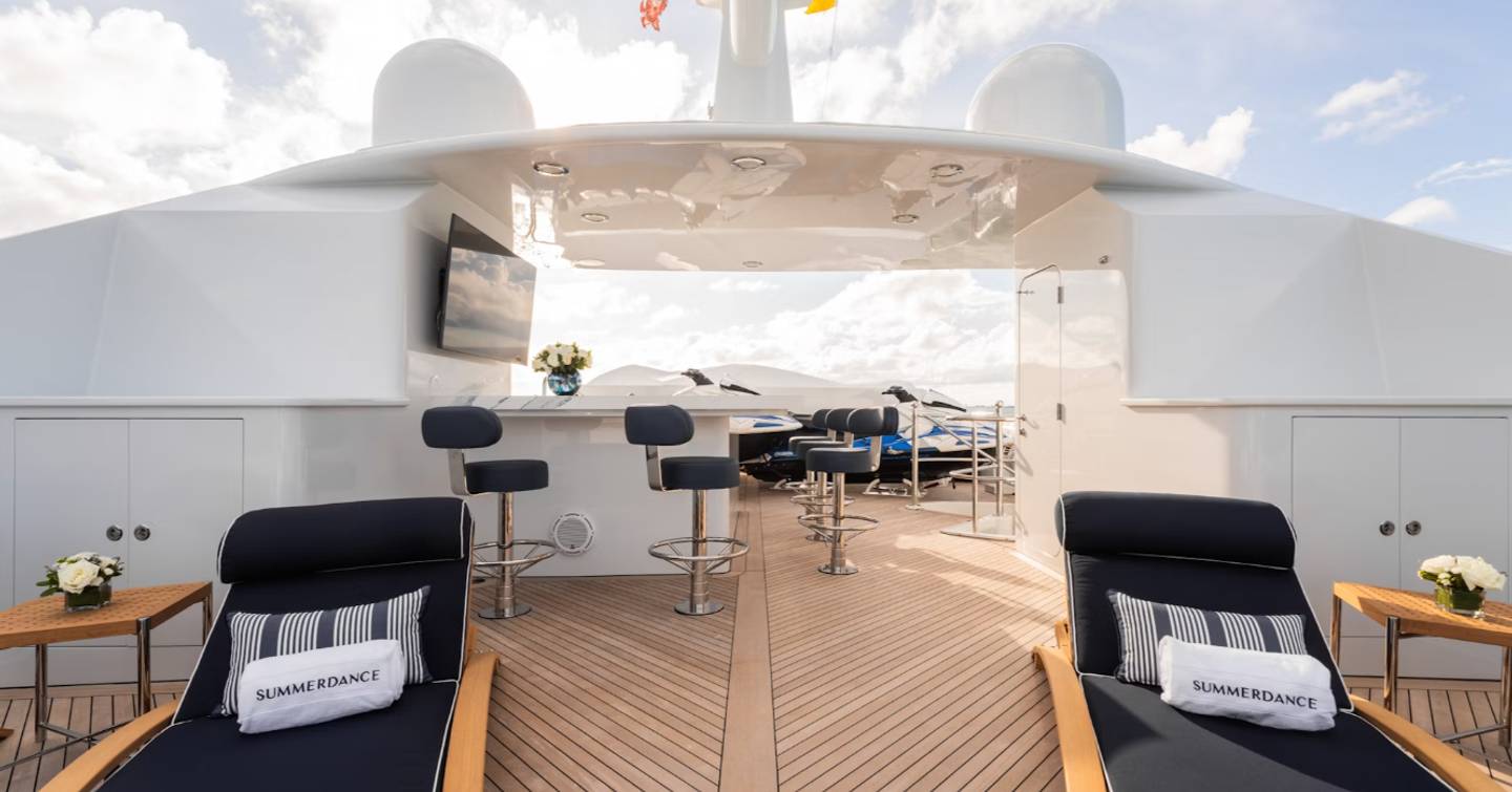 Superyacht Summer Dance sundeck with navy sun loungers and bar area