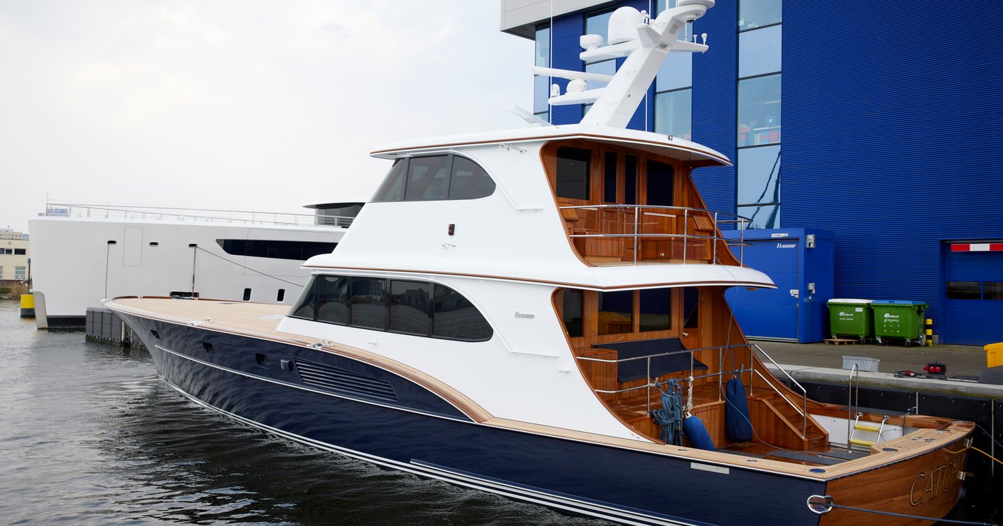 Side view of motor yacht CATCH, docked at Feadship Amsterdam facility.