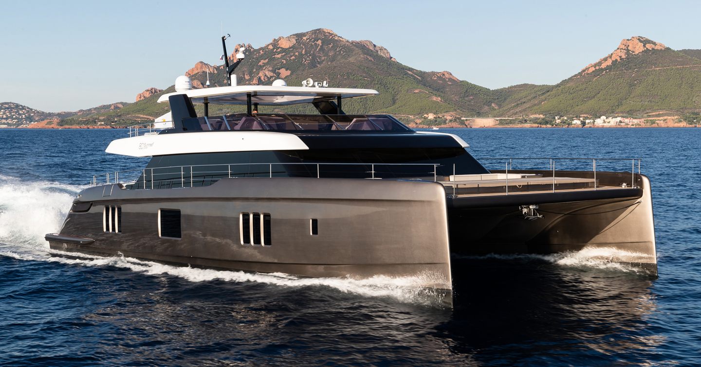 Sunreef 80 Power catamaran underway, mountainous terrain in background.