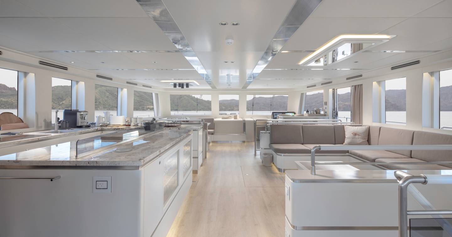 Catamaran GloriaMaris main saloon with neutral palette, marbled galley and U-shaped beige seating