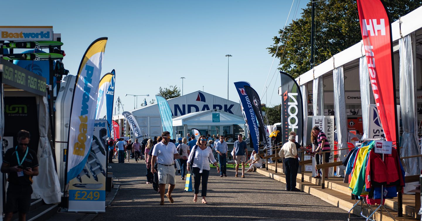 Line up of Southampton boat show exhibitors on both sides of walkway. Visitors walking along looking at tents.