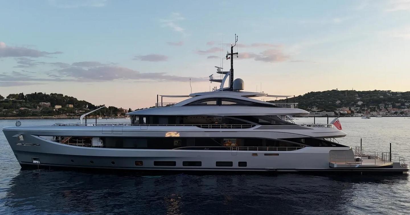 Motor yacht Perla at anchor during sunset, with an illuminated sign 