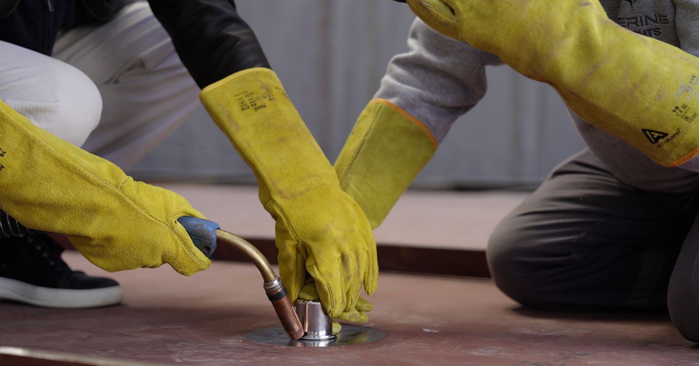 Welding of coin onto Bering 165 Explorer Yacht hull during keel laying ceremony