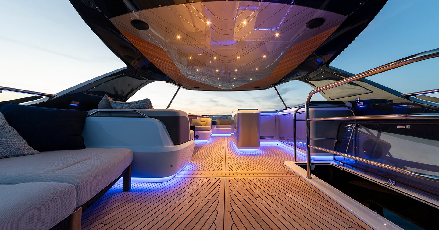 Flybridge lounge area aboard the Galeon 620 Fly with night lighting and hardtop shelter.