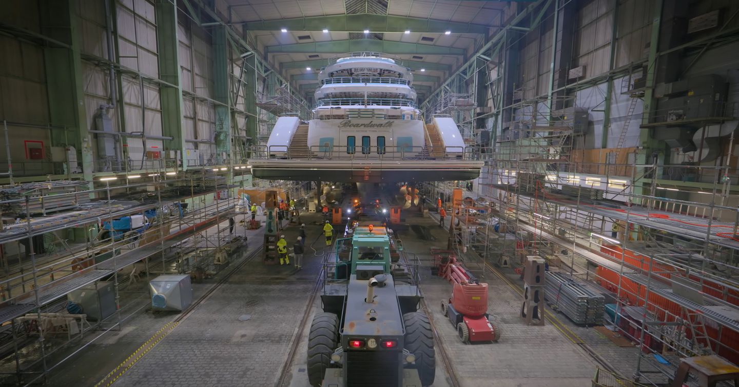 Aft shot of Superyacht Boardwalk in Lurssen shipyard with workers underneath 