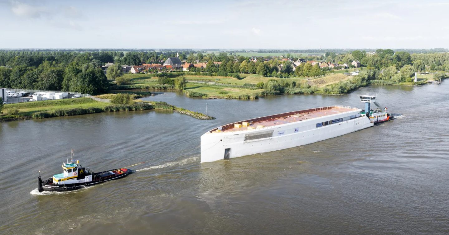 Feadship Project 832 Superyacht Hull behind tugboat being transported in the netherlands