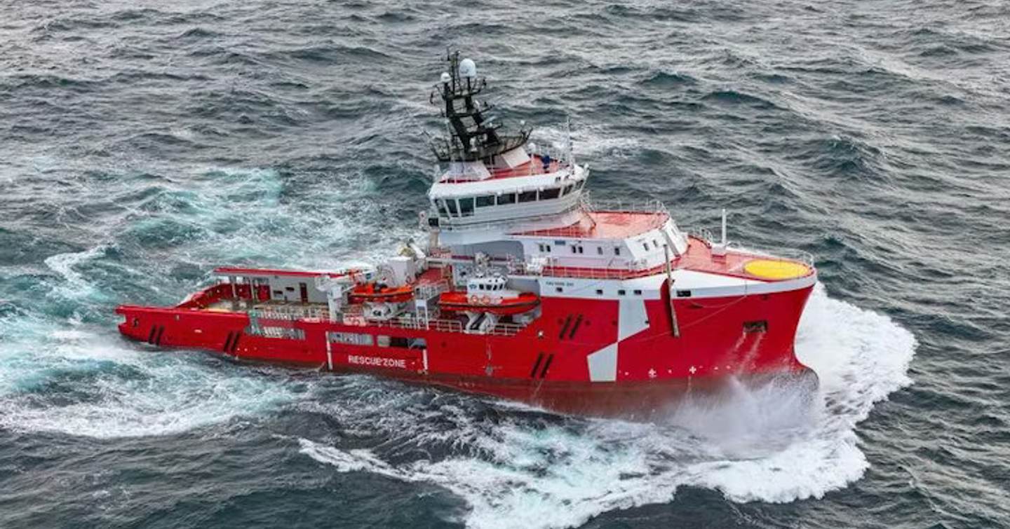 Expedition yacht Ocean Falcon pre-conversion with red hull under way in rough seas 