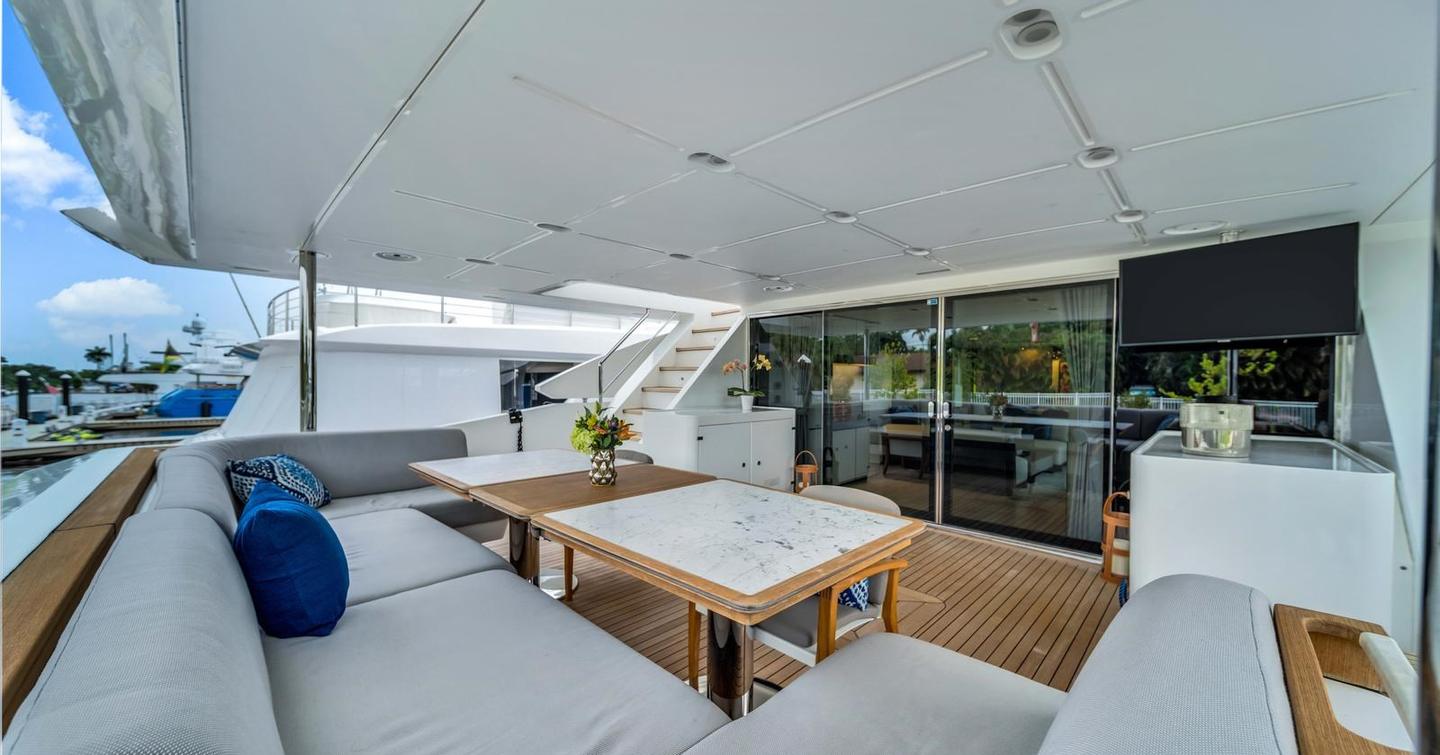 Superyacht One & Only aft deck with grey U-shaped seating, mounted TV and glass sliding doors 