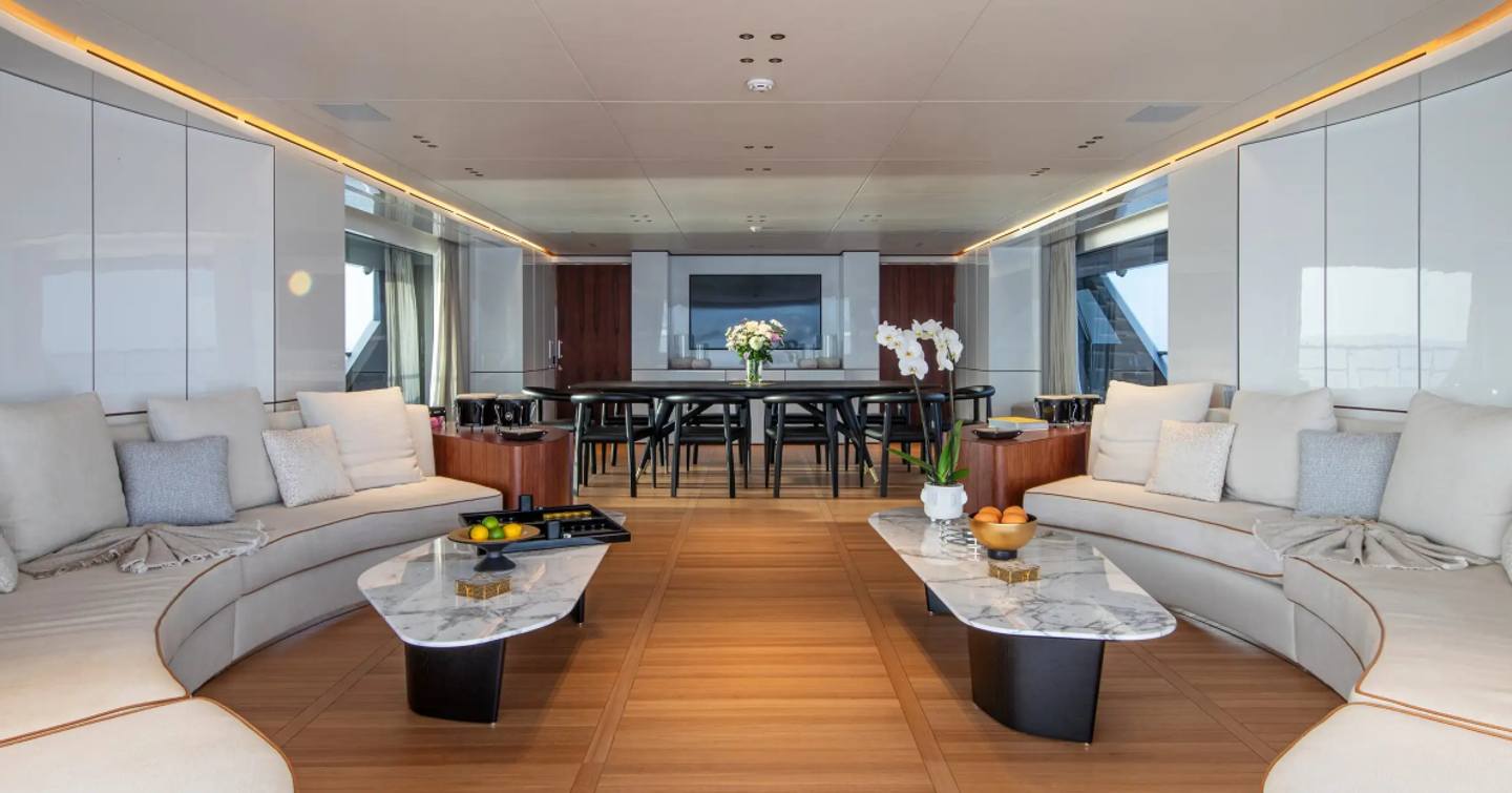 Superyacht Tosun main saloon with dual curved white sofa and forward dining area 