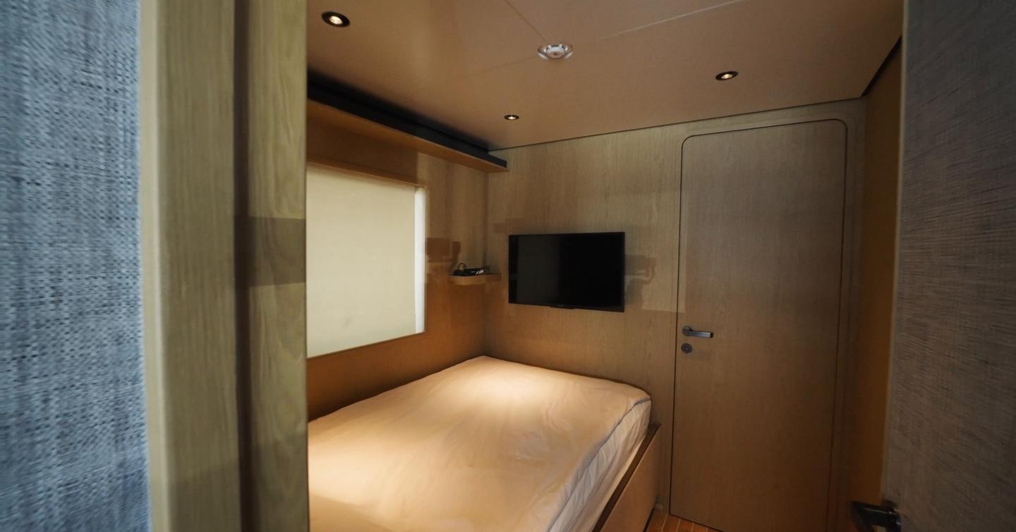 Custom Line Navetta 38 captain’s cabin with single bed, wall-mounted TV and direct access near the bridge