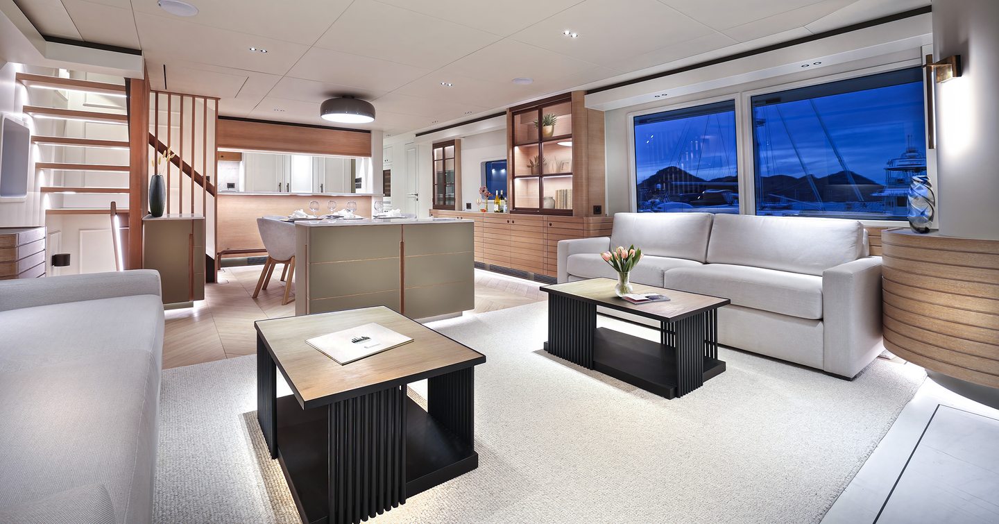 Nordhavn 80 Motor Yacht main saloon with white sofas and wooden dual coffee tables 