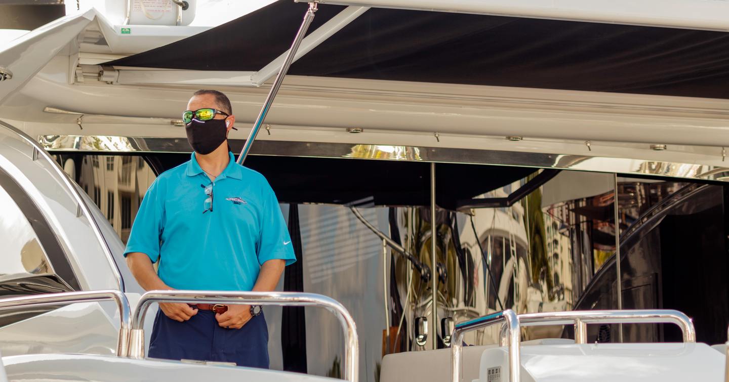 MYS visitor standing on aft area of yacht with a face mask on.