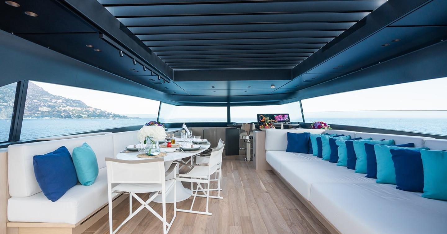 Superyacht Ami's flybridge with shaded dining and seating areas