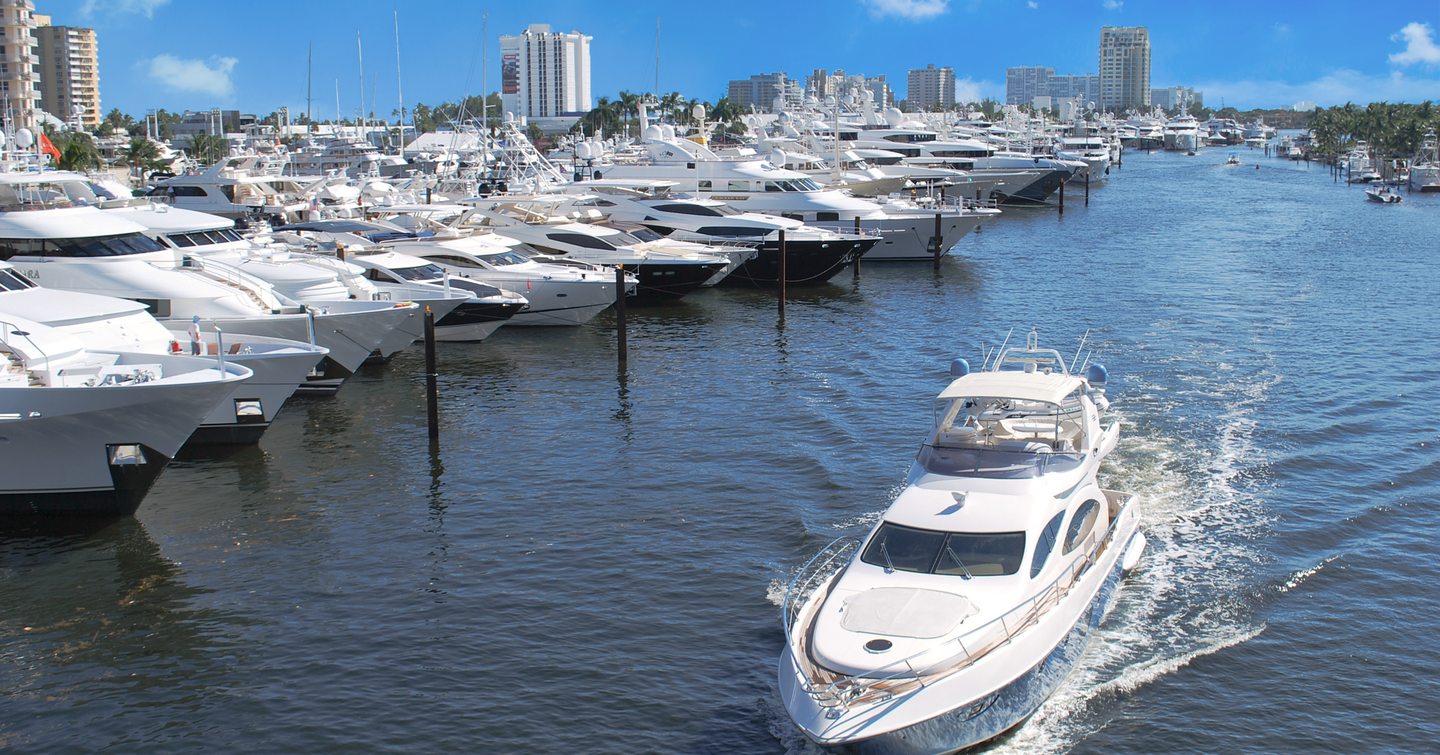 Motor yachts moored along portside with one motor yacht travelling towards camera, during Fort Lauderdale International Boat Show.