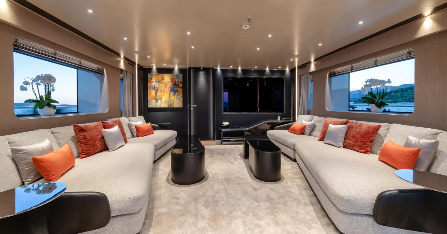 Superyacht Kinda upper saloon with orange accents and mounted TV