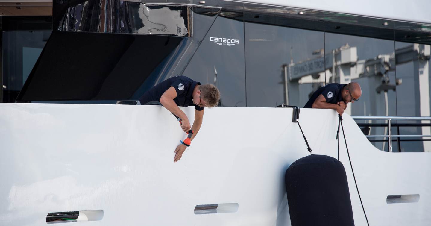 Two crew members cleaning yacht exterior