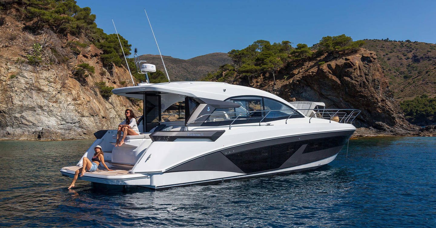 Beneteau Gran Turismo 45 motor yacht at anchor with people sitting on aft