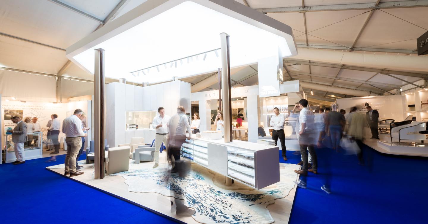 Exhibitor stand on blue carpet at the Monaco Yacht Show.