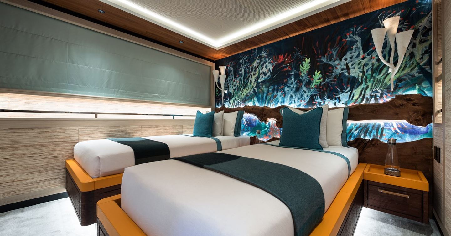 Motor yacht King Benji's twin cabin with jungle prints, blue cushions and low lighting