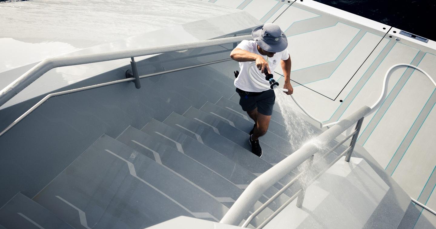 Crew member hosing down Oceanco superyacht Leviathan aft stairs 