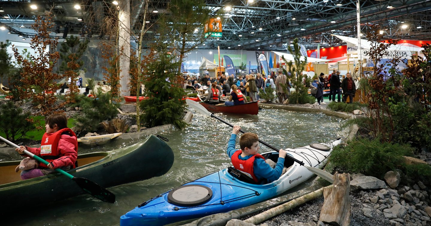 River course at Boot Dusseldorf. Young visitors paddling in canoes along course.