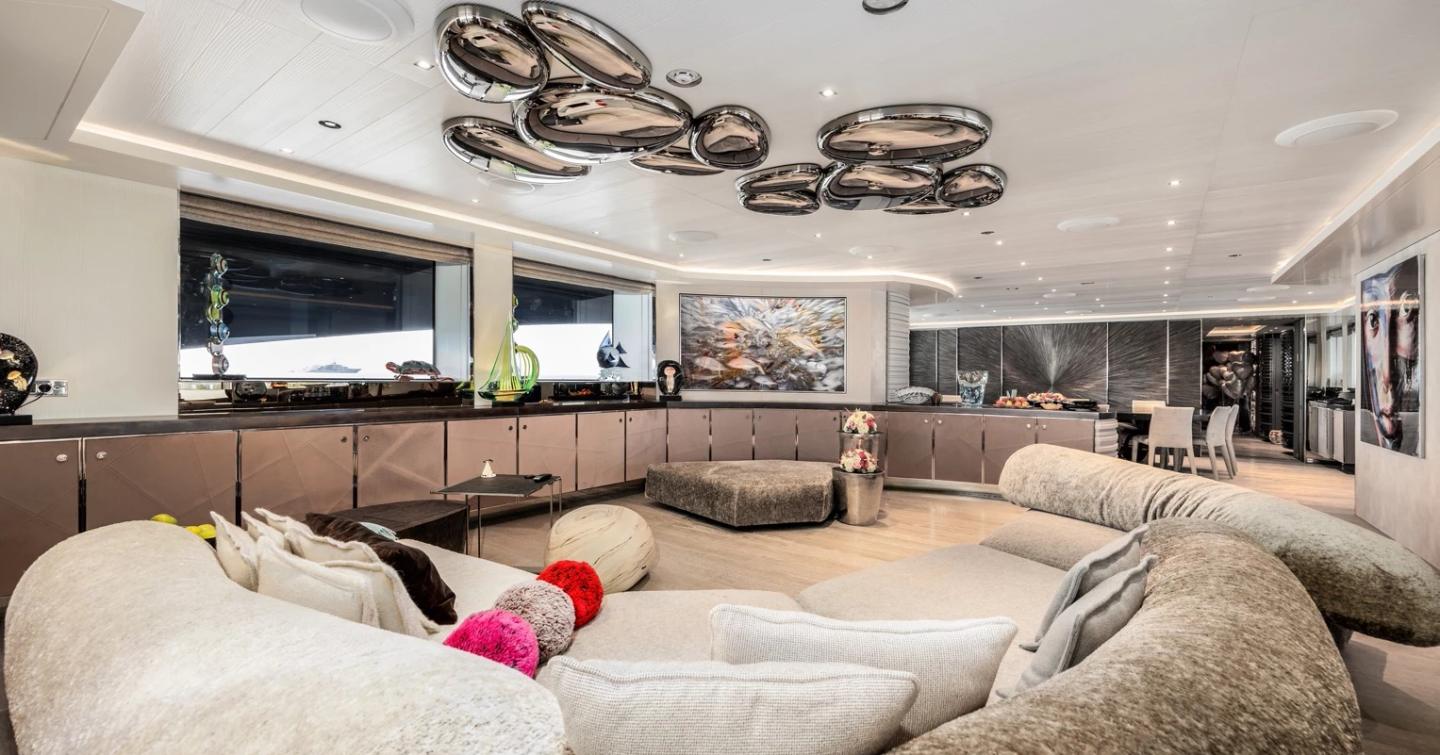 Superyacht Seanna's main saloon with curved seating and mounted TV